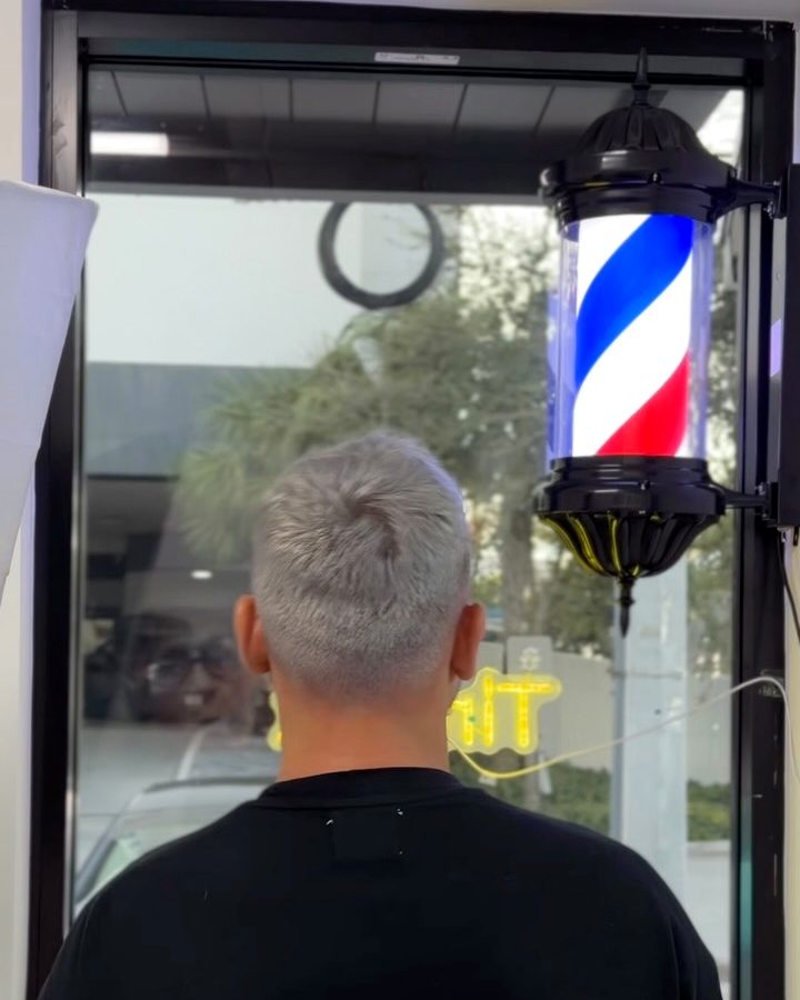 Back of a client's silver-grey haircut next to the salon's barber pole