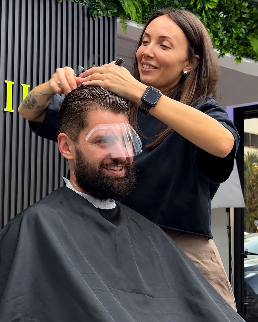 Tina finishing the haircut of a bearded client in the salon chair